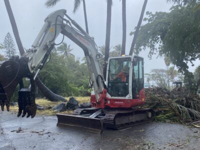 THE RESTORATION OF PUNALUʻU 14 Excavator removing fallen palm trees and storm debris along the road at Punaluʻu in Kaʻū, Hawaii