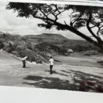 Golfers playing at Sea Mountain Golf Course near Punaluʻu with Kaʻū landscape in the background, early 1970s Hawaiʻi